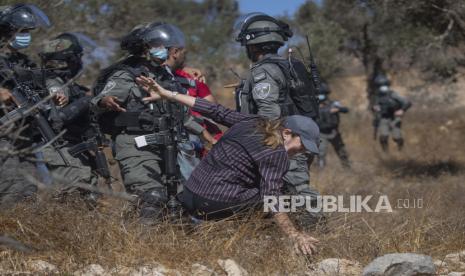 Polisi perbatasan Israel mendorong seorang wanita Palestina saat membubarkan jurnalis dan petani menggunakan granat kejut dan gas air mata, di desa Burqa Tepi Barat, Timur Ramallah, Jumat, 16 Oktober 2020. Warga Palestina bentrok dengan polisi perbatasan Israel di Tepi Barat pada hari Jumat. selama upaya mereka untuk mencapai dan memanen kebun zaitun mereka di dekat pos terdepan pemukim Yahudi. 