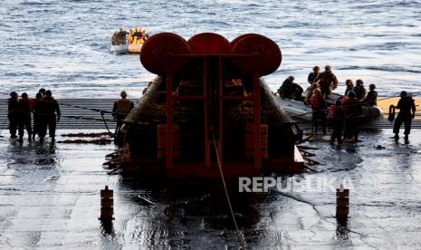 Anggota tim selam Angkatan Laut AS kembali setelah Orion Capsule (C) NASA dibawa ke dek sumur U.S.S. Portland, setelah tercebur mengikuti Artemis I Moon Mission tanpa awak yang berhasil dilihat dari atas kapal U.S.S. Portland di Samudra Pasifik di lepas pantai Baja California, Meksiko, 11 Desember 2022. Sebuah misi 26 hari membawa pesawat ruang angkasa Orion ke bulan dan kembali yang menyelesaikan uji terbang bersejarah yang bertepatan dengan peringatan 50 tahun pendaratan Apollo 17 di bulan, terakhir kali astronot NASA berjalan ke sana.