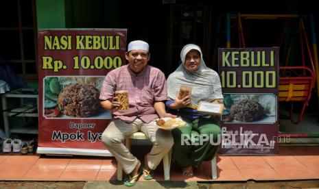 Hadjiah (54 tahun) dan Herman (69) pemilik UMKM Dapoer Mpok Iyah berpose saat di sela aktivitas di rumahnya di kawasan Cakung, Jakarta Timur, Selasa (20/2/2024). Dapoer Mpok Iyah merupakan UMKM binaan PT Jakarta Industrial Estate Pulogadung (PT JIEP) menjual beragam jenis makanan seperti camilan steik bawang, nasi kebuli hingga melayani jasa catering. Selain mendapatkan bantuan modal dari PT JIEP, UMKM ini juga mendapatkan pendampingan sertifikasi halal sehingga berdampak pada peningkatan omsetnya.