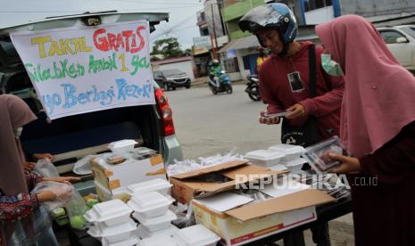 Sejumlah pengendara sepeda motor dan pejalan kaki menghampiri tempat pembagian takjil gratis yang disediakan warga di jalan Syeh Yusuf, Kendari, Sulawesi Tenggara, Sabtu (25/4/2020). Di bulan suci Ramadhan banyak cara yang dilakukan Umat Islam untuk mendapatkan pahala salah satunya dengan memberi makanan secara gratis atau takjil kepada muslim yang akan berbuka puasa