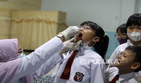 Petugas puskesmas melakukan vaksinasi polio tahap kedua menggunakan vaksin polio oral bivalen (BOPV) kepada siswa SD (ilustrasi).