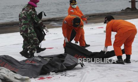  Tim penyelamat membawa kantong jenazah berisi jasad manusia yang ditemukan dari perairan tempat jet penumpang Sriwijaya Air jatuh, di Pelabuhan Tanjung Priok di Jakarta, Indonesia, Minggu, 10 Januari 2021. Tim penyelamat Indonesia mengeluarkan bagian tubuh, potongan pakaian, dan potongan logam dari Laut Jawa Minggu pagi, sehari setelah Boeing 737-500 dengan puluhan orang di dalamnya jatuh tak lama setelah lepas landas dari Jakarta, kata para pejabat.