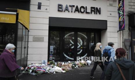  Para pejalan kaki berjalan di luar gedung konser Bataclan dengan karangan bunga yang menandai peringatan 5 tahun serangan 13 November 2015, di Paris, Jumat, 13 November 2020. Pengadilan AS akan Putuskan Apakah Media Sosial Bertanggung Jawab atas Serangan Militan