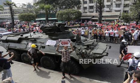 Demonstran berkumpul di jalan di mana tentara dan kendaraan lapis baja dikerahkan selama protes di luar Bank Sentral Myanmar (CBM) di Yangon, Myanmar, 15 Februari 2021. Junta militer Myanmar pada 15 Februari menghentikan layanan internet dan mengerahkan pasukan serta kendaraan lapis baja di seluruh negara dalam tanda-tanda meningkatnya kekuatan untuk menekan protes massa terhadap kudeta militer dan gerakan pembangkangan sipil yang tumbuh yang telah melumpuhkan layanan pemerintah.