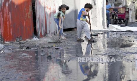 Anak-anak Palestina mengepel di luar rumah mereka setelah pemboman Israel di kamp pengungsi Maghazi di Jalur Gaza pada Minggu, 5 November 2023.