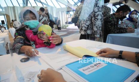 Istri pekerja yang mendapatkan Manfaat Layanan Tambahan (MLT) dari program Jaminan Hari Tua (JHT) menyelesaikan proses administrasi saat proses akad kredit massal  di Serpong, Tangerang (30/11).  Bank BTN berkolaborasi dengan Kementerian Ketenagakerjaan dan BP Jamsostek menggelar akad massal kredit rumah pekerja MLT program Jaminan Hari Tua guna memperluas fasilitas pembiayaan kepada pada pekerja diantaranya fasilitas kredit kepemilikan rumah dan renovasi rumah dan menargetkan realisasi kredit MLT tersebut mencapai Rp100 miliar hingga akhir tahun 2021.Foto: Tahta Aidilla/Republika.