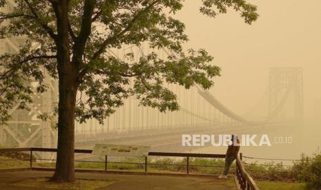 Seorang pria berbicara di teleponnya saat dia melihat menembus asap kebakaran hutan di Kanada di Jembatan George Washington di Fort Lee, NJ, 7 Juni 2023.