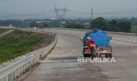 Pekerja menyemprotkan air saat membersihkan sisa material di jalan tol fungsional Solo-Yogyakarta. Polisi mengimbau pemudik mewaspadai sejumlah jalur rawan bencana di DIY.