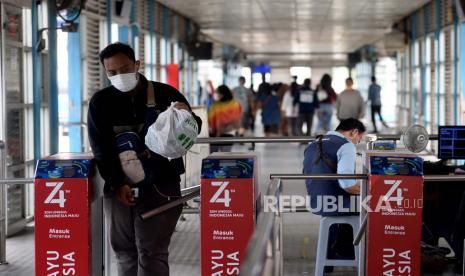 Penumpang dengan mengenakan masker berjalan keluar halte transjakarta saat pemberlakuan Pembatasan Sosial Berskala Besar (PSBB) pada hari ke dua di Halte Harmoni, Jakarta, Sabtu (11/4). DKI Jakarta masih menjadi pusat episentrum COVID-19 di Indonesia