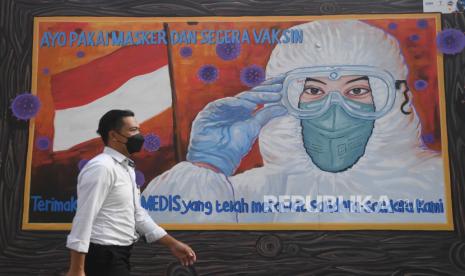 Warga melintas di dekat mural bertema Covid-19. Ketua Satuan Tugas Covid-19 IDI Zubairi Djoerban memprediksi, kasus Covid-19 di Indonesia masih terus naik drastis hingga pertengahan Maret 2022.