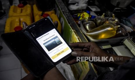 Pedagang mengambil gambar kartu tanda penduduk (KTP) pembeli yang akan membeli minyak goreng curah rakyat (MGCR) di salah satu kios di Pasar Kosambi, Kota Bandung, Senin (27/6/2022). Pemerintah berencana akan mewajibkan masyarakat menggunakan aplikasi PeduliLindungi atau menunjukkan Nomor Induk Kependudukan (NIK) pada KTP saat membeli minyak goreng curah rakyat (MGCR) seharga Rp14 ribu per liter mulai pertengahan Juli mendatang. Foto: Republika/Abdan Syakura