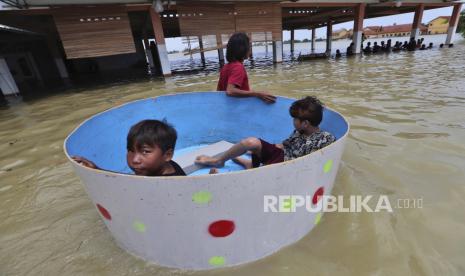 10 Kecamatan di Kabupaten Bekasi Masih Terendam Banjir. Anak-anak duduk di dalam bak saat banjir di Bekasi, Indonesia, Senin, 22 Februari 2021. Ribuan warga dievakuasi di pinggiran ibu kota Indonesia di tengah banjir setelah tanggul Sungai Citarum jebol, kata pejabat Senin.