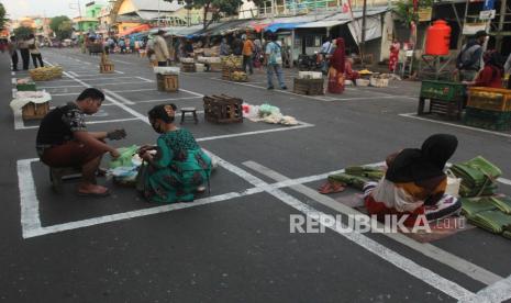 Pedagang menjual dagangannya di depan Pasar Pegirian, Surabaya, Jawa Timur, Ahad (31/5/2020). Perusahaan Daerah (PD) Pasar Surya Kota Surabaya menerapkan jaga jarak (physical distancing) di pasar itu dengan membuat garis petak-petak bagi pedagang dan mulai ditempati hari ini Minggu (31/5) sebagai langkah pencegahan penyebaran COVID-19