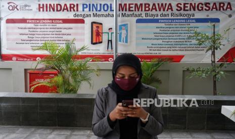 Warga berada di dekat poster edukasi waspada fintech ilegal di kantor Otoritas Jasa Keuangan (OJK) Yogyakarta, Rabu (4/11/2020). 