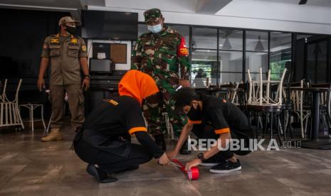 Petugas gabungan mengawasi karyawan restoran memasang tanda jaga jarak saat terjaring razia PSBB. Lima restoran di Jakpus ditutup karena masih melayani makan di tempat saat PSBB. Ilustrasi.