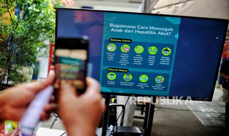 Warga mengambil gambar informasi pencegahan hepatitis akut saat kegiatan layanan kesehatan gratis di Pasar Induk Kramat Jati, Jakarta Timur, Selasa (24/5/2022). Kasus hepatitis yang ada saat ini dijuluki sebagai hepatitis misterius karena belum diketahui penyebabnya.