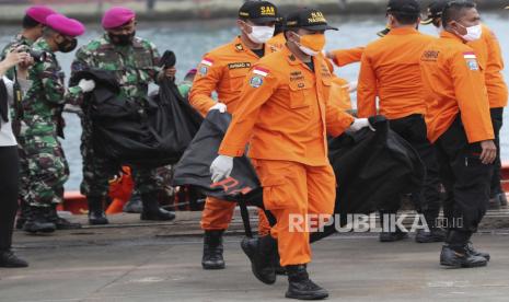 Tim penyelamat membawa kantong jenazah yang berisi jasad manusia yang ditemukan dari perairan tempat jet penumpang Sriwijaya Air jatuh, di Pelabuhan Tanjung Priok di Jakarta, Indonesia, Minggu, 10 Januari 2021. Tim penyelamat Indonesia mengeluarkan bagian tubuh, potongan pakaian, dan potongan logam dari Laut Jawa Minggu pagi, sehari setelah Boeing 737-500 dengan puluhan orang di dalamnya jatuh tak lama setelah lepas landas dari Jakarta, kata para pejabat.