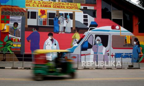 Sebuah gambar kecepatan rana lambat menunjukkan orang India mengemudi melewati grafiti untuk menciptakan kesadaran di antara orang-orang tentang Covid-19 di Bangalore, India, 12 Oktober 2020. Grafiti ini dibuat oleh proyek seni 