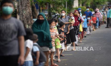 Sejumlah warga mengantre saat mengambil makanan berbuka puasa gratis di Jalan Cempaka Putih Tengah, Jakarta, Ahad (18/4). Sekitar 400-600 paket takjil yang disajikan mulai dari kue, kolak, gorengan, mie ayam, nasi kotak, serta es buah dibagikan secara gratis setiap harinya pada pukul 17.00 selama bulan ramadhan dengan menerapkan protokol kesehatan. Prayogi/Republika.