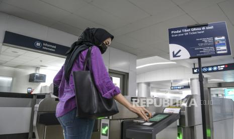 Seorang calon penumpang memindai kode batang (QR code) di Stasiun MRT Bundaran Hotel Indonesia, Jakarta