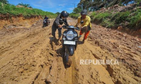 Warga mendorong sepeda motornya melewati jalan rusak di Desa Persiapan Air Merah, Muaro Jambi, Jambi, Selasa (9/5/2023). Jalan menuju kawasan permukiman di bagian tenggara Kabupaten Muaro Jambi tersebut rusak parah sepanjang belasan kilometer dan berlubang hingga kedalaman 80 cm.  