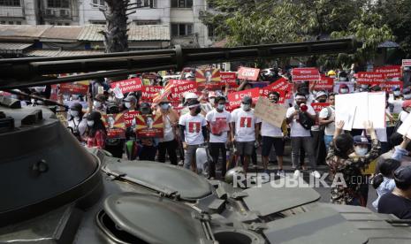 Demonstran berkumpul di dekat jalan di mana tentara dan kendaraan lapis baja dikerahkan selama protes di luar Bank Sentral Myanmar (CBM) di Yangon, Myanmar, 15 Februari 2021. Junta militer Myanmar pada 15 Februari menghentikan layanan internet dan mengerahkan pasukan serta kendaraan lapis baja di seluruh penjuru Myanmar. negara dalam tanda-tanda meningkatnya kekuatan untuk menekan protes massa terhadap kudeta militer dan gerakan pembangkangan sipil yang tumbuh yang telah melumpuhkan layanan pemerintah.