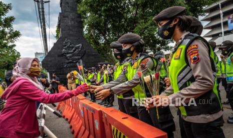 Seorang buruh yang tergabung dalam Konfederasi Serikat Pekerja Nasional (KSPN) Jateng memberikan bunga kepada sejumlah polisi wanita yang berjaga saat aksi damai menolak UU Cipta Kerja Omnibus Law di depan kompleks DPRD Jateng, Semarang, Jawa Tengah, pada 2020 lalu. Setelah dinilai inkonstitusional bersyarat oleh MK, Presiden Jokowi kemudian menerbitkan Perppu Cipta Kerja. (ilustrasi)