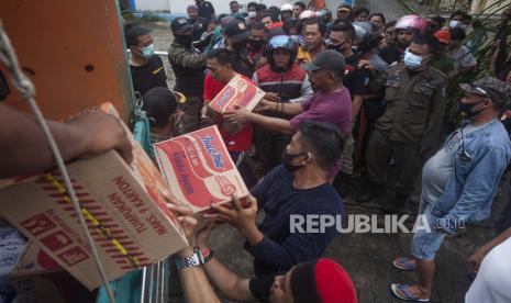 Warga yang terdampak gempa mengantri untuk mendapatkan bantuan pangan di Mamuju, Sulawesi Barat, Indonesia, Minggu, 17 Januari 2021. Tim penyelamat mengambil lebih banyak mayat dari puing-puing rumah dan bangunan yang roboh akibat gempa berkekuatan 6,2 skala Richter, sementara insinyur militer berhasil membuka kembali jalan yang rusak untuk membuka akses bagi barang bantuan.