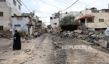 Warga Palestina berjalan di sepanjang jalan yang rusak di kamp pengungsi Jenin menyusul serangan Israel semalaman di kota Jenin, Tepi Barat, (25/1/2024).