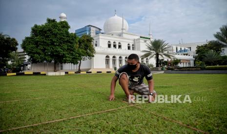 Petugas mengatur jarak shaf untuk shalat Idul Fitri 1442 Hijriah di area Masjid Agung Al-Azhar, Jakarta Selatan, Rabu (12/5). Pengurus Masjid Agung Al-Azhar akan menyelenggarakan Shalat Idul Fitri 1442 Hijriah di lapangan dan area parkir dengan menerapkan protokol kesehatan yang ketat serta membatasi kapasitas maksimum jamaah mencapai 50 persen. 