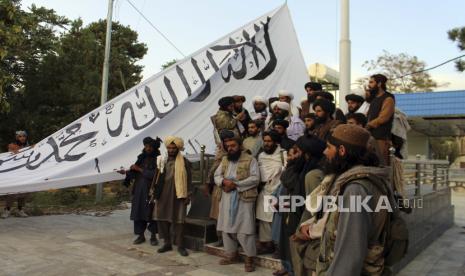 Taliban berpose untuk foto sambil mengibarkan benderanya di rumah gubernur provinsi Ghazni, di Ghazni, tenggara, Afghanistan, Minggu, 15 Agustus 2021.