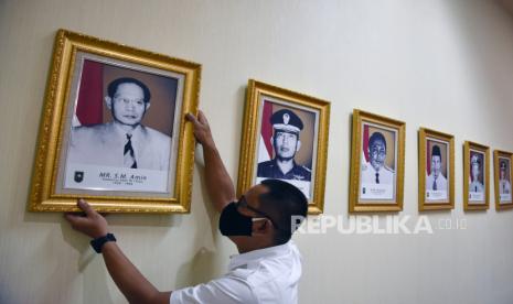 Seorang pegawai merapikan letak foto Gubernur Riau pertama, Sultan Mohammad (SM) Amin Nasution, di Kantor Gubernur Riau, Kota Pekanbaru, Senin (9/11/2020). Presiden Joko Widodo akan memberikan gelar Pahlawan Nasional kepada dua tokoh pada peringatan Hari Pahlawan 10 November, salah satunya SM Amin Nasution yang pernah menjabat sebagai Gubernur Riau dan Sumatera Utara yang pertama.