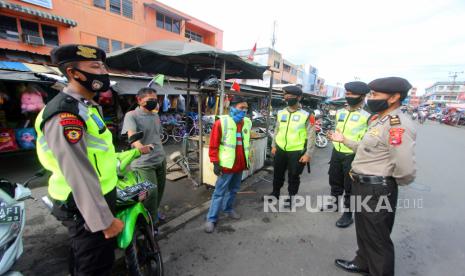 Polisi memberikan penjelasan mengenai aturan pemerintah saat patroli penegakan aturan Pembatasan Sosial Berskala Besar (PSBB) di kawasan Pasar Baru Banjarmasin, Kalimantan Selatan, Senin (27/4/2020). Kegiatan tersebut sebagai upaya POLRI untuk mendukung aturan pemerintah saat PSBB di Kota Banjarmasin serta memberikan edukasi tentang penanganan dan pencegahan penyebaran COVID-19 di tempat keramaian