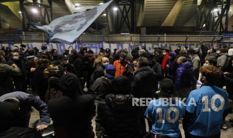  Orang-orang berkumpul di luar Stadion San Paolo, Napoli, untuk memberi penghormatan kepada legenda sepak bola Diego Maradona, di Naples, Italia, Rabu, 25 November 2020. Diego Maradona telah meninggal. Pemain sepak bola hebat Argentina itu termasuk di antara para pemain terbaik yang pernah ada dan yang memimpin negaranya meraih gelar Piala Dunia 1986 sebelum kemudian berjuang dengan penggunaan kokain dan obesitas. Dia meninggal di usia 60 tahun. 