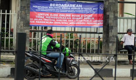 Pengemudi ojek daring melihat aplikasi di gawainya di dekat halte yang dipasang spanduk larangan berhenti di jalan Kapten Muslihat, Kota Bogor, Jawa Barat, Rabu (15/9/2021). Pemerintah Kota Bogor melarang ojek daring untuk mangkal atau menunggu pesanan di enam ruas jalan yang merupakan jalur Sistem Satu Arah (SSA) yang menghubungkan antara Kebun Raya Bogor dengan Istana Kepresidenan Bogor karena mengganggu ketertiban umum. 