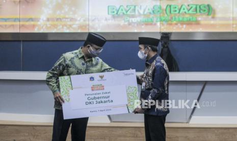 Gubernur DKI Jakarta Anies Baswedan menunaikan zakat secara simbolis kepada Ketua Baznas (Bazis) DKI Jakarta Akhmad H. Abubakar di Balai Kota DKI Jakarta, Kamis (7/4/2022). Pemerintah Provinsi DKI Jakarta bersama Baznas (Bazis) DKI Jakarta bekerja sama untuk penyaluran zakat infaq dan shadaqah di lingkungan wilayah Pemprov DKI Jakarta, dengan target sebesar Rp 66 miliar untuk pembangunan Pesantren Tahfidz Disabilitas di Lebak Bulus, Jakarta. Republika/Putra M. Akbar