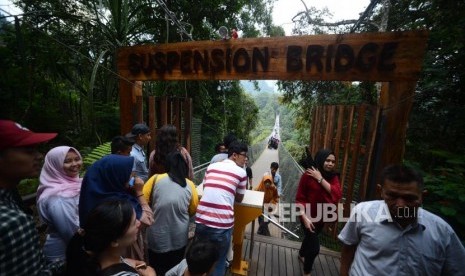 Wisatawan antre untuk melintasi  Situ Gunung Suspension Bridge di Taman Nasional Gunung Gede Pangrango, Kadudampit, Sukabumi.