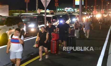 Calon penumpang pesawat berjalan di Jalan Tol Bali Mandara setelah mobil yang ditumpanginya terjebak kemacetan saat akan menuju ke Bandara Internasional I Gusti Ngurah Rai di Badung, Bali, Jumat (29/12/2023). Kemacetan itu terjadi sejak Jumat sore akibat padatnya kendaraan yang melintas di kawasan jalan akses Bandara I Gusti Ngurah Rai pada musim liburan akhir tahun.