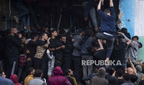 Warga Palestina berjuang untuk membeli roti dari toko roti di Rafah, Jalur Gaza, Ahad, (18/2/2024).