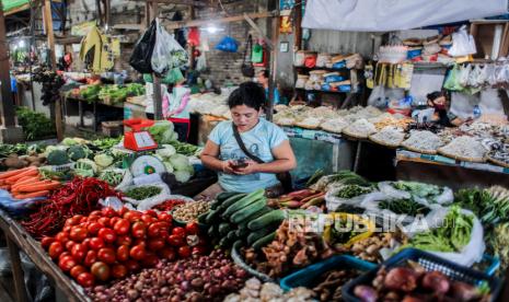  Seorang penjual sayur memeriksa ponselnya saat menunggu pelanggan di pasar di Medan, Sumatera Utara, Indonesia, 05 November 2020.  omisi Pengawas Persaingan Usaha (KPPU) Kanwil I Medan mengingatkan para distributor tidak menahan pasokan bahan pokok yang permintaannya meningkat.