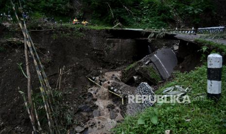 Petugas mengamati jembatan yang roboh di Talegong, Kabupaten Garut, Jawa Barat, Minggu (10/1/2021). Curah hujan yang tinggi di kawasan tersebut mengakibatkan jembatan Awisuti roboh hingga setengah badan jalan dan memutus akses penghubung antara Pangalengan, Talegong, Cisewu, dan Ranca Buaya bagi kendaraan roda empat. 