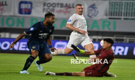 Pesepak bola Persita Tangerang Marios Ogkmpoe (kiri) menendang bola dan berupaya diadang penjaga gawang Persis Solo Muhamad Riyandi (kanan) dalam pertandingan Liga 1 2024/2025 di Stadion Pakansari, Cibinong, Kabupaten Bogor, Jawa Barat, Ahad (8/12/2024). Persita Tangerang mengalahkan Persis Solo dengan skor 2-0. Gol Persita dicetak Marios Ogkmpoe di menit ke-28 dan Ahmad Nur Hardianto menit 67.