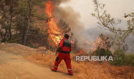  Petugas pemadam kebakaran bekerja di daerah Mazi yang diselimuti asap saat kebakaran hutan berguling menuruni bukit menuju pantai, memaksa orang untuk dievakuasi, di Bodrum, Mugla, Turki, Minggu, 1 Agustus 2021. Lebih dari 100 kebakaran hutan telah dikendalikan di Turki, menurut para pejabat. Menteri kehutanan mentweet bahwa lima kebakaran terus berlanjut di tujuan wisata Antalya dan Mugla.