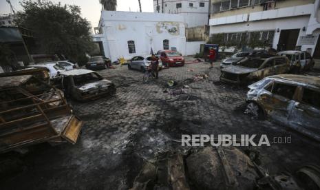 Warga Palestina memeriksa lokasi ledakan di rumah sakit al-Ahli, di Kota Gaza, Rabu, (18/10/2023). 