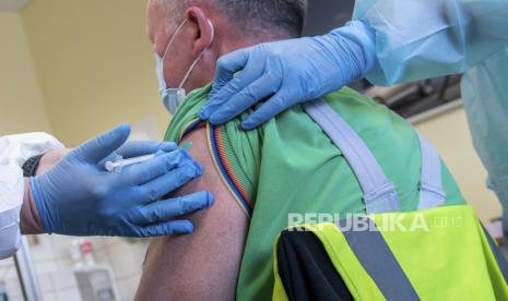 Steffen Martin, seorang karyawan di pabrik Volkswagen Saxony menerima vaksinasi AstraZeneca terhadap penyakit COVID-19 dari seorang dokter perusahaan Volkswagen di Zwickau, Jerman, Selasa, 30 Maret 2021.