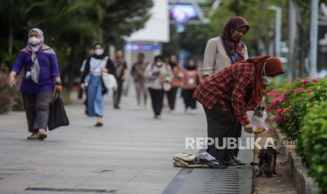 Pekerja memberi makan kucing liar di kawasan Sudirman, Jakarta, Selasa (21/11/2023).  Pemerintah Provinsi DKI Jakarta menaikan Upah Minimum Provinsi (UMP) DKI Jakarta menjadi Rp 5.067.381, dari sebelumnya Rp 4.901.798 atau naik sekitar Rp 165.583.