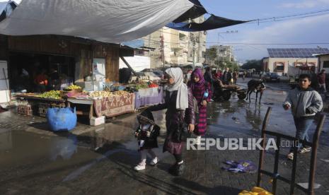 Warga Palestina berjalan melewati sebuah toko di Rafah, Jalur Gaza, selama pengeboman Israel yang sedang berlangsung di Jalur Gaza pada Selasa, 14 November 2023.