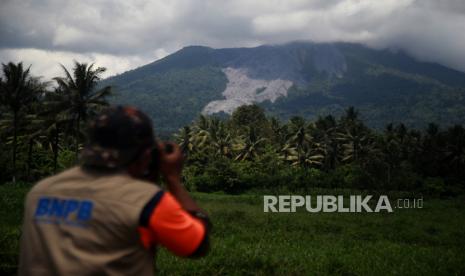 Petugas BNPB memotret kondisi Gunung Ibu pasca erupsi yang terlihat dari Desa Tokuoko Kabupaten Halmahera Barat, Maluku Utara, Kamis (9/5/2024). Pusat Vulkanologi dan Mitigasi Bencana Geologi (PVMBG) mengumumkan kenaikan status Gunung Ibu dari sebelumnya waspada level II menjadi siaga level III yang terhitung pada Rabu (8/5) pukul 10.00 WIT, sehingga masyarakat di daerah itu dihimbau agar tidak beraktivitas dalam radius 3 kilometer. 