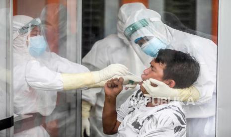  Petugas kesehatan dengan pakaian hazmat mengumpulkan sampel spesimen melalui kaca plexiglass selama uji coba swab COVID-19 di Medan, Sumatera Utara, Indonesia. Satuan Tugas Penanganan COVID-19 Sumut mencatat terus terjadi penambahan pasien COVID-19 yang meninggal atau sudah mencapai 705 orang.