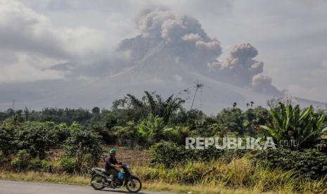 Gunung Sinabung Erupsi Lanjutan. Seorang pria mengendarai sepeda motornya saat Gunung Sinabung memuntahkan abu vulkanik saat erupsi di Karo, Sumatera Utara, Indonesia, 03 Maret 2021. Gunung Sinabung, salah satu gunung berapi teraktif di Indonesia, meletus pada 02 Maret, memuntahkan material vulkanik setinggi 5.000 meter di udara. Indonesia berada di Cincin Api Pasifik, yang menyumbang 80 persen aktivitas seismik dunia.